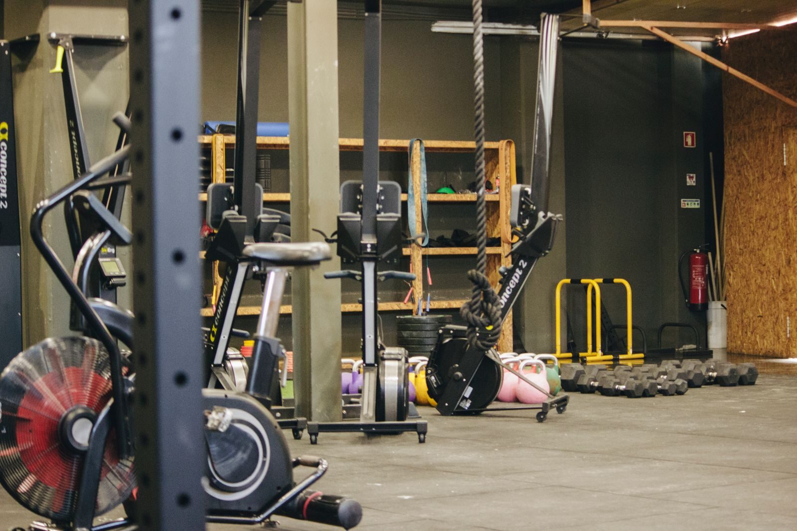 Une salle de cross-training équipée : rig, rameur, vélo et kettlebells